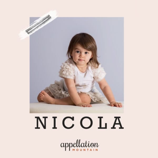 toddler girl with brown hair wearing white and gray dress looking at camera; baby name Nicola