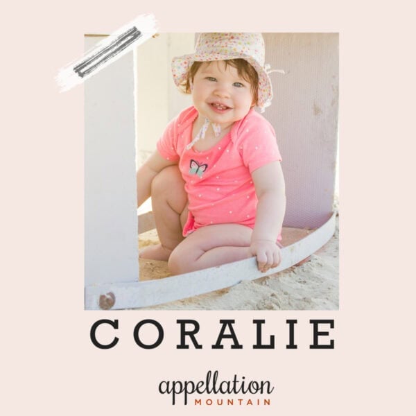 baby girl wearing beach hat and coral outfit sitting on sand; baby name Coralie