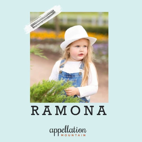 girl wearing white fedora, white long sleeve tee and denim overalls with long blonde hair outdoors on farm; baby name Ramona
