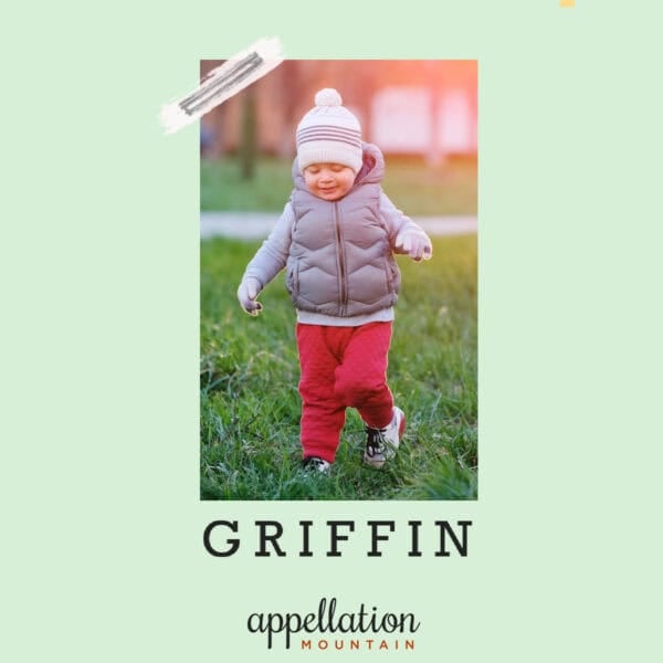 toddler boy in red pants, gray vest, and knit hat running outside on grassy field; baby name Griffin