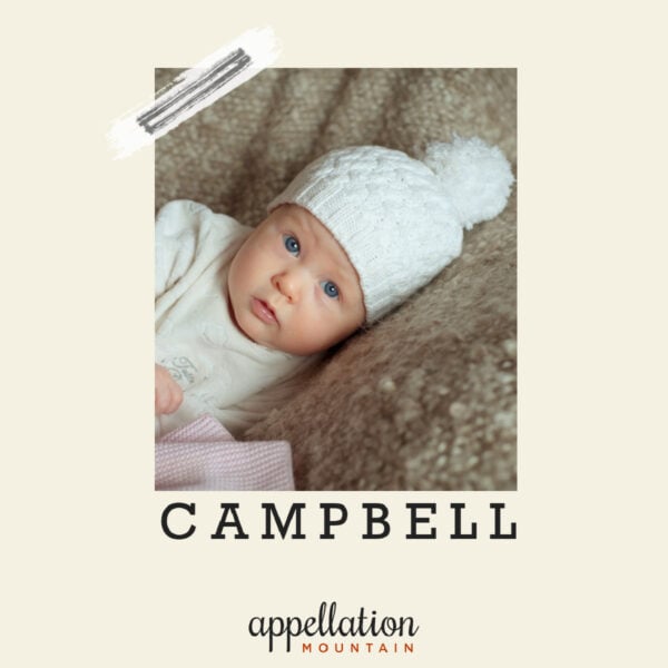 baby wearing white knit cap with white pom pom and matching sweater on brown blanket; baby name Campbell