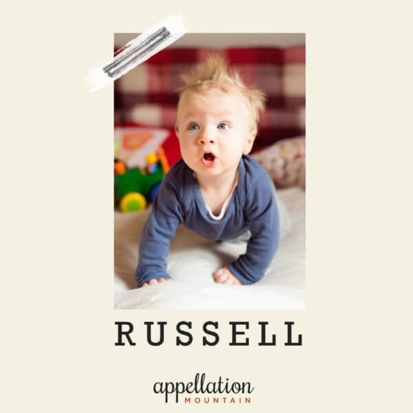 baby boy with reddish brown hair pushed up on arms wearing blue long sleeved shirt; baby name Russell