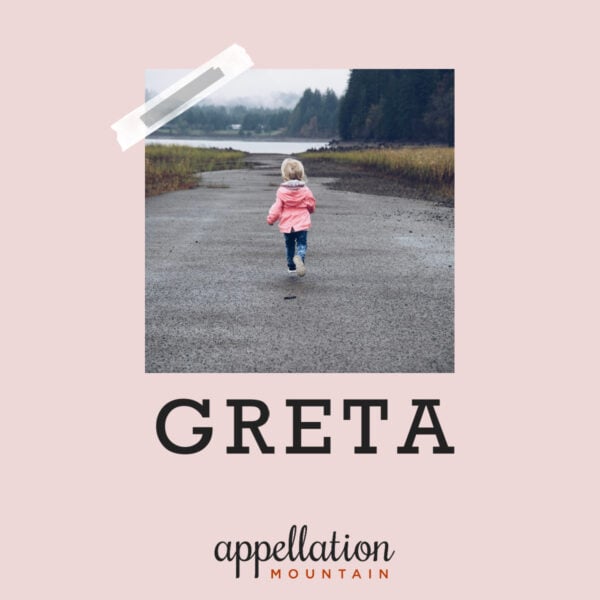 girl child in pink coat and jeans running away from camera on a road, toward a lake or river, in a wooded area, "baby name Greta"