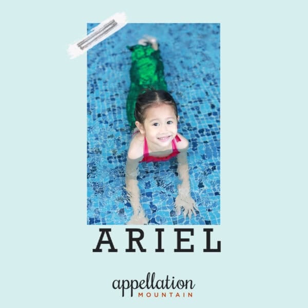 girl child resting on her stomach in shallow swimming pool with blue tile, wearing mermaid costume with sparkly green tail; baby name Ariel