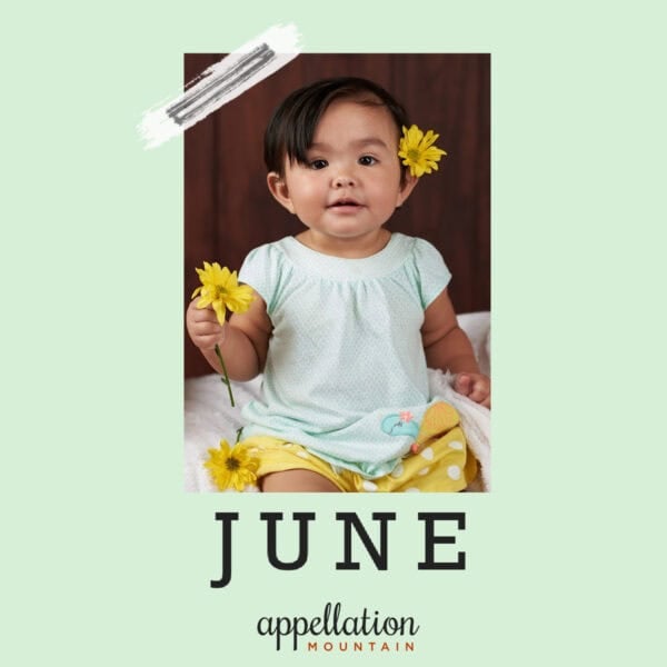 Latina girl wearing light blue dress with yellow flower in her hair, holding a yellow flower; baby name June