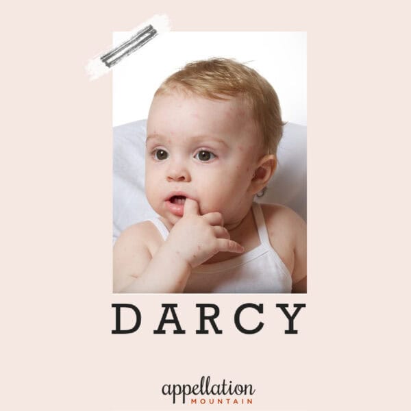 baby with light brown curls chewing on finger; baby name Darcy