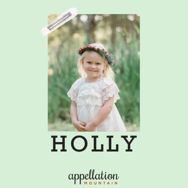 girl child wearing white dress and wreath of holly standing outside in a field; baby name Holly