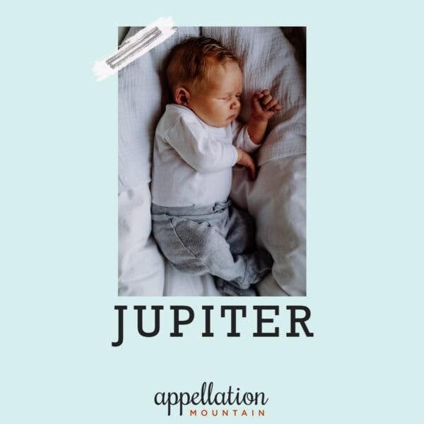 baby wearing white top and gray pants sleeping on side; baby name Jupiter