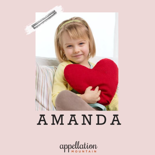 girl child with short blone hair holding red heart pillow "baby name Amanda"