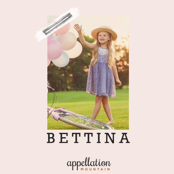 girl wearing blue sundress and sunhat standing next to pink balloons tied to a bicycle outdoors in a field, "baby name Bettina"