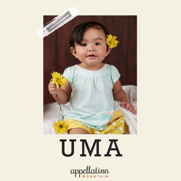 baby girl with dark hair wearing yellow flowers in her hair and a white dress; baby name Uma