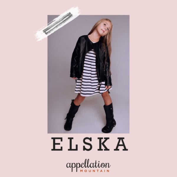 girl with blonde hair wearing striped dress, black jacket and boots, "baby name Elska"