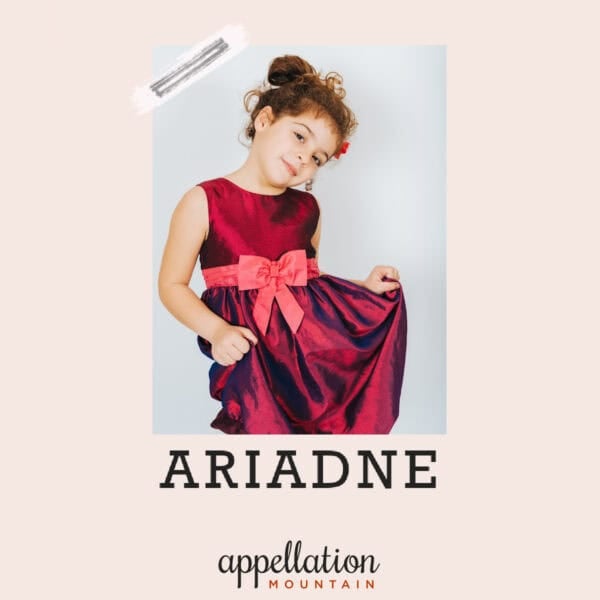 girl with curly brown hair pinned up wearing dark red dress with lighter red sash; baby name Ariadne