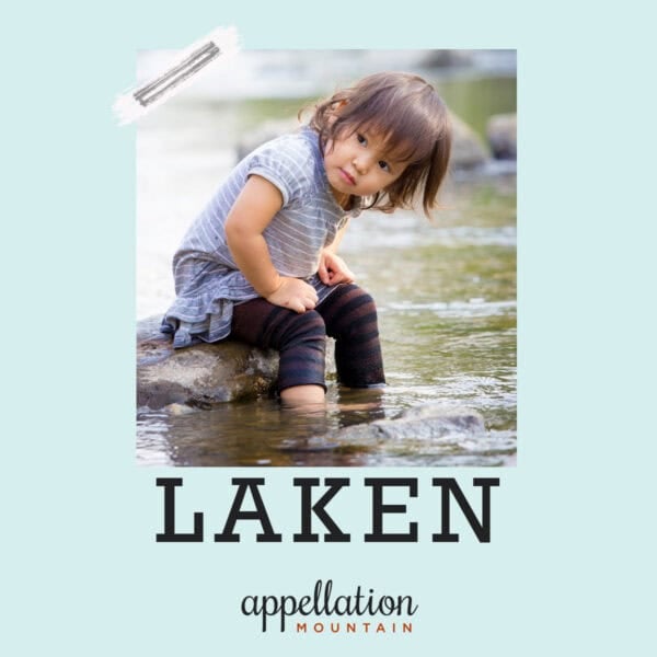 girl child sitting on rock in shallow water wearing striped tee, skirt, and navy leggings; baby name Laken