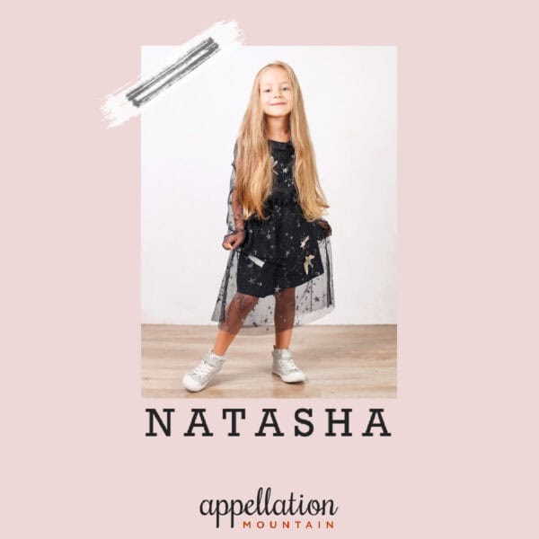 girl with long blonde hair wearing black dress and sneakers; "baby name Natasha"