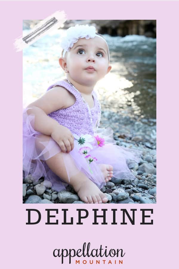 baby girl in lilac dress with floral headband sitting outside; baby name Delphine