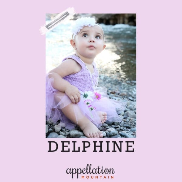 baby girl in lilac dress with floral headband sitting outside; baby name Delphine