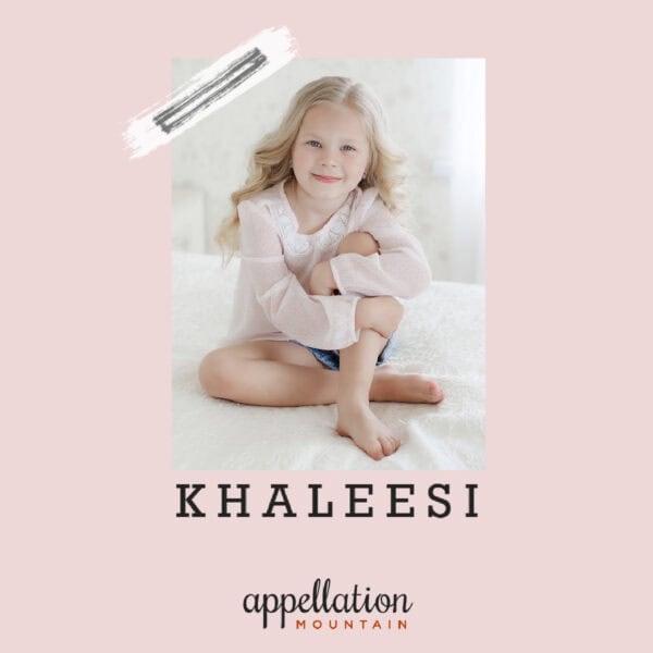 young girl with long blonde hair wearing pink long sleeve top and shorts, sitting with legs folded; baby name Khaleesi