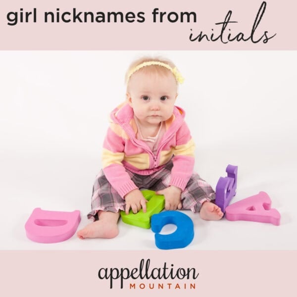 baby girl wearing pink top sitting up holding letters; girl names from initials