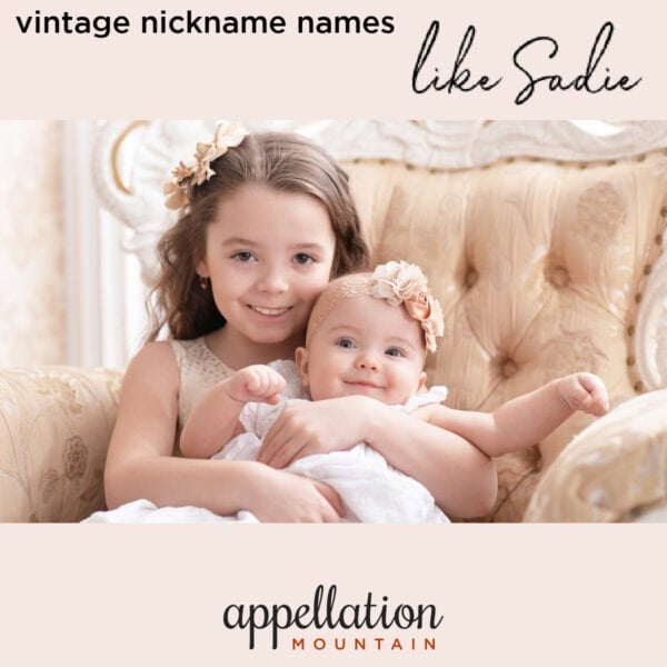 girl with brown hair holding baby girl, both with pink headbands, seated on elegant chair "vintage nicknames for girls like Sadie"
