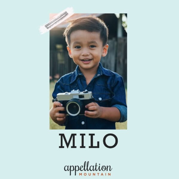 dark-haired boy wearing navy button-up shirt and holding camera; baby name Milo