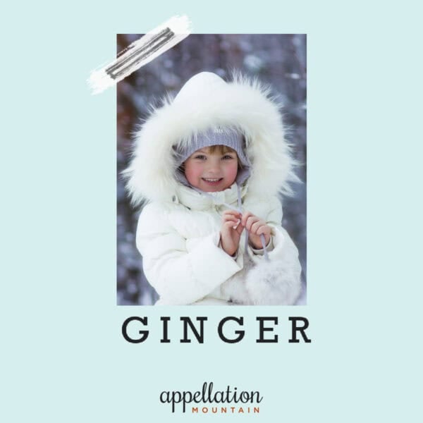girl child wearing white coat with fur-trimmed hood standing outdoors; baby name Ginger
