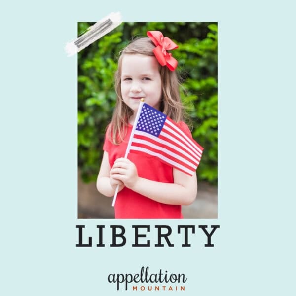 girl child wearing red shirt and red hair bow holding American flag; baby name Liberty