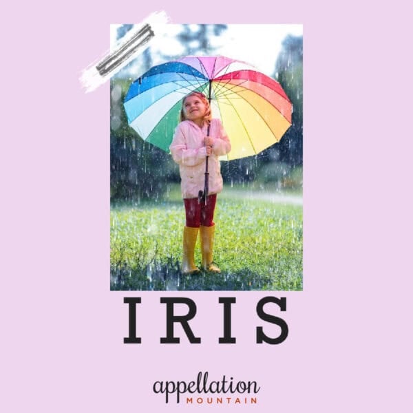girl child wearing pink raincoat holding rainbow umbrella outside on green grass; baby name Iris