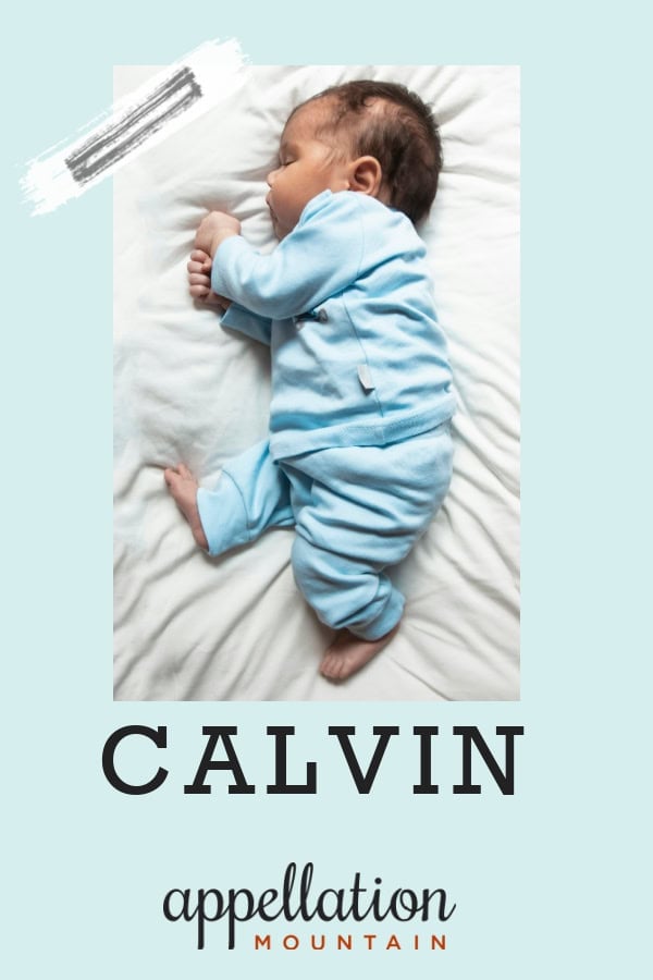 sleeping baby boy with dark hair lying on his side wearing blue sleeper; baby name Calvin