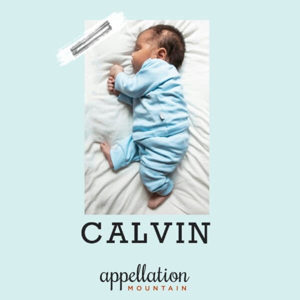sleeping baby boy with dark hair lying on his side wearing blue sleeper; baby name Calvin