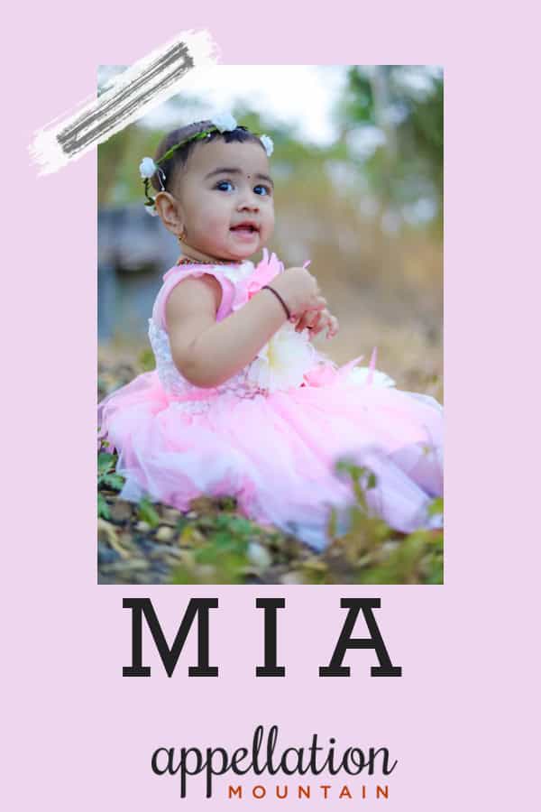girl of Indian descent wearing pale lavender fancy dress sitting in field; baby name Mia