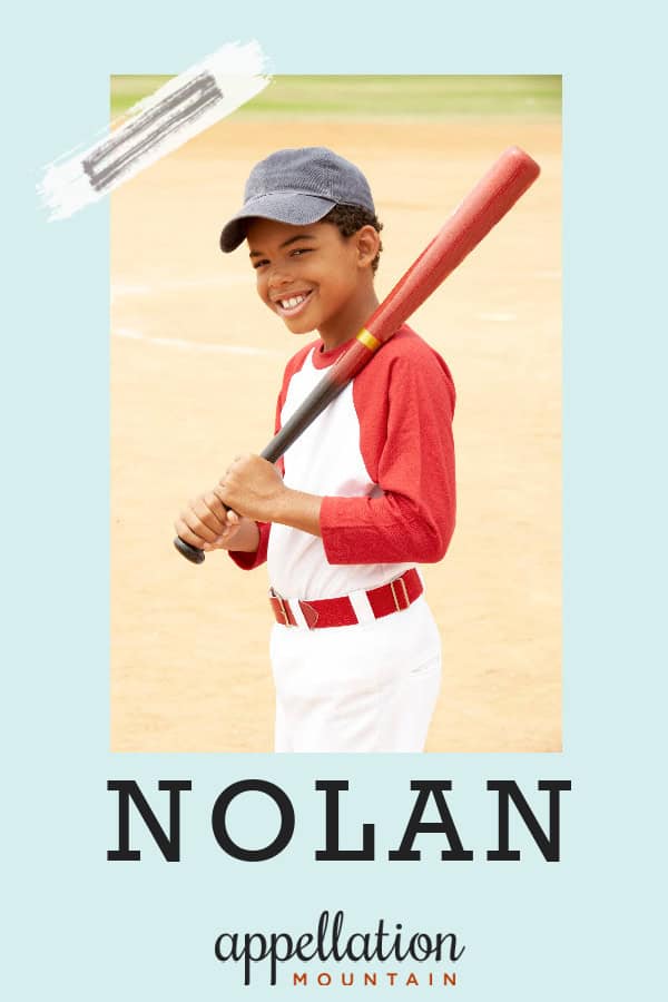 smiling boy wearing baseball uniform and hat with baseball bat over shoulder; baby name Nolan