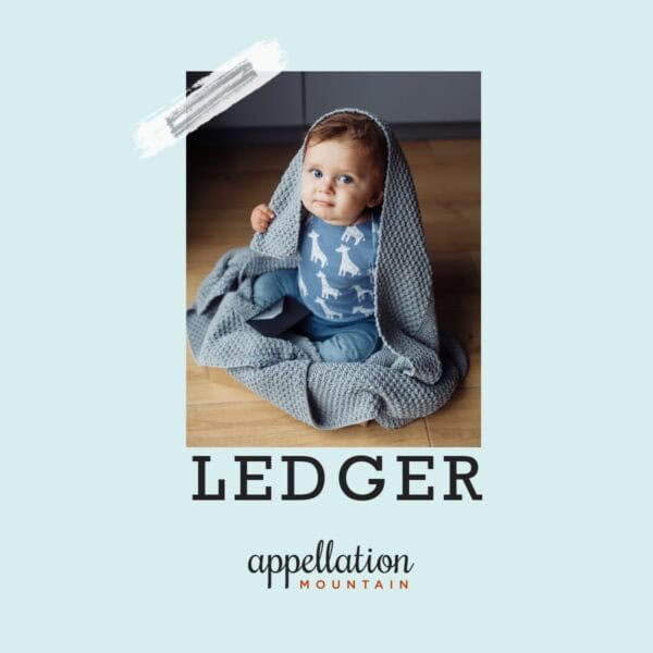 baby boy wearing blue print sleeper with gray blanket over his shoulders; baby name Ledger