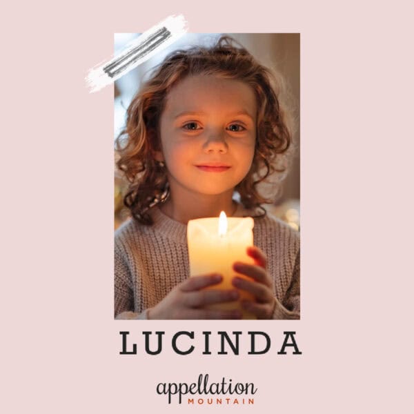 girl with wavy blonde hair wearing a light pink sweater holding a lit candle; baby name Lucinda