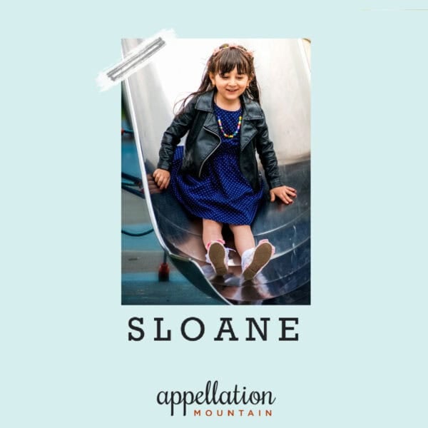 girl child with long dark hair wearing navy dress and black leather jacket; baby name Sloane