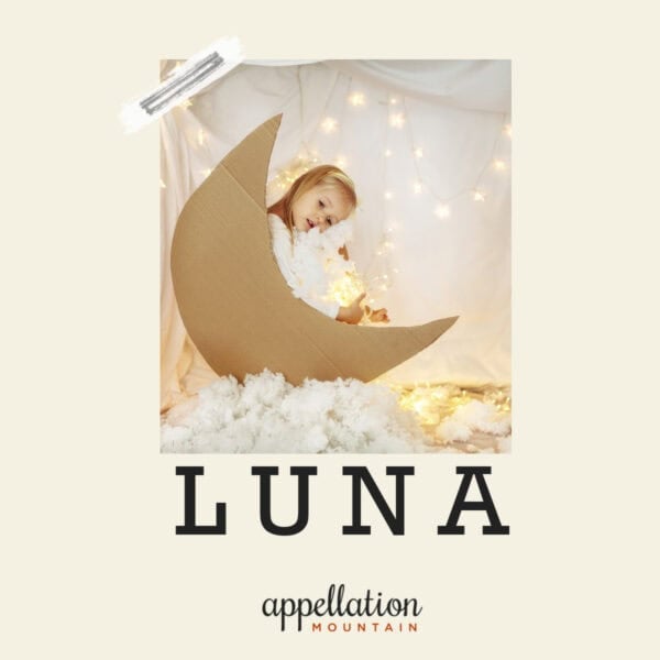 little blonde girl sitting in brown cardboard moon cutout "baby name Luna"