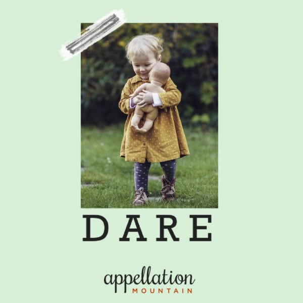 toddler girl with blonde hair wearing vintage yellow dress holding doll outside on grass "baby name Dare"