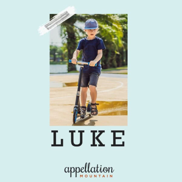 young boy with blonde hair wearing dark tee shirt, shorts, and baseball hat, riding scooter outside on trail; baby name Luke