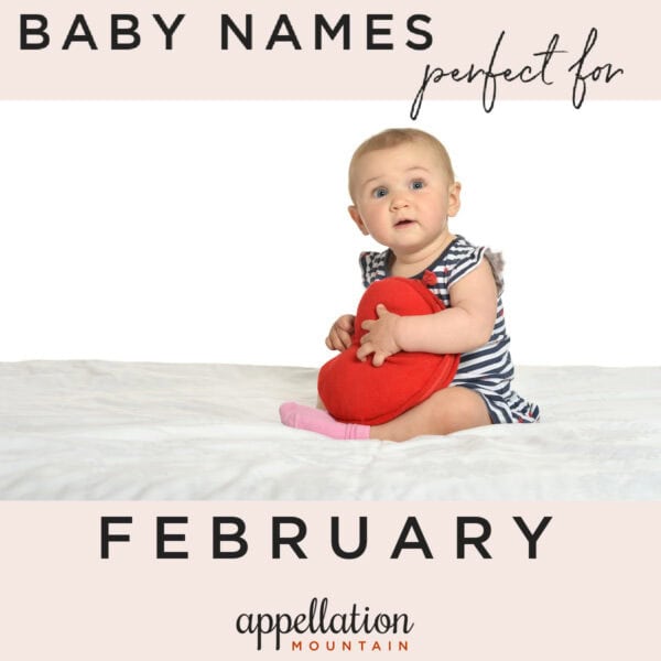 baby wearing striped outfit and holding red heart-shaped pillow; February baby names