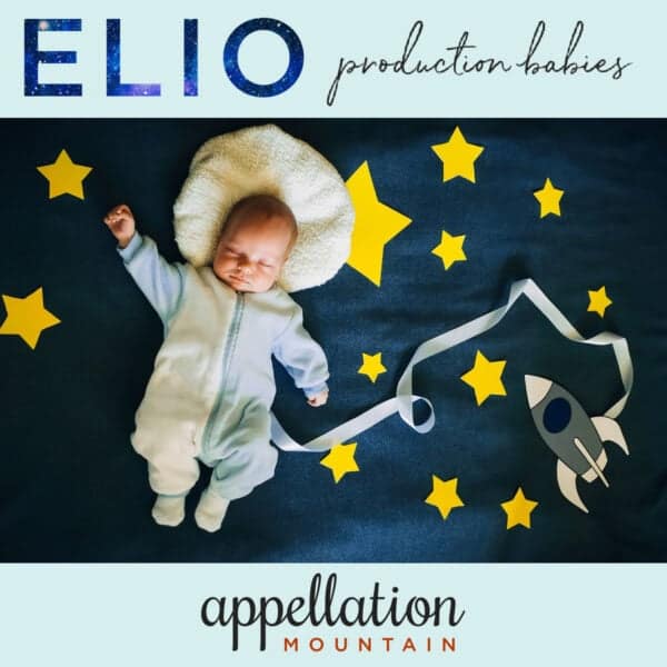 baby in blue onesie against dark blue paper night sky with yellow stars and a spaceship; Elio production babies