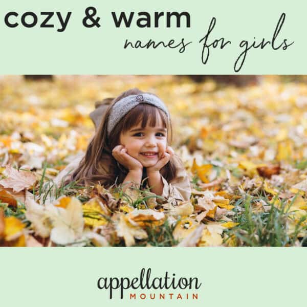 brown haired girl child wearing knit headband lying in field of yellow autumn leaves with head in hands; Cozy Girl Names