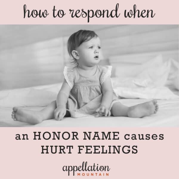 baby girl with brown hair wearing dress and sitting on bed; honor name causes hurt feelings