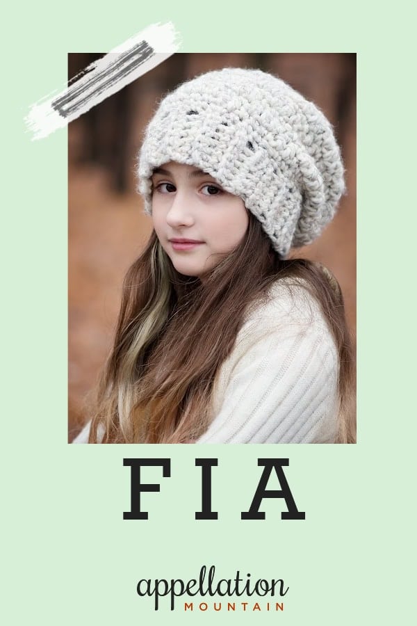 girl child with long dark hair outside wearing ivory knit hat and sweater; baby name Fia