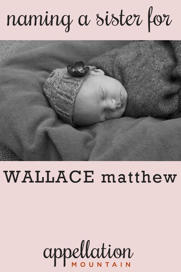 sleeping baby girl wearing knit hat with flower wrapped in dark blanket laying on dark blanket; sister for Wallace
