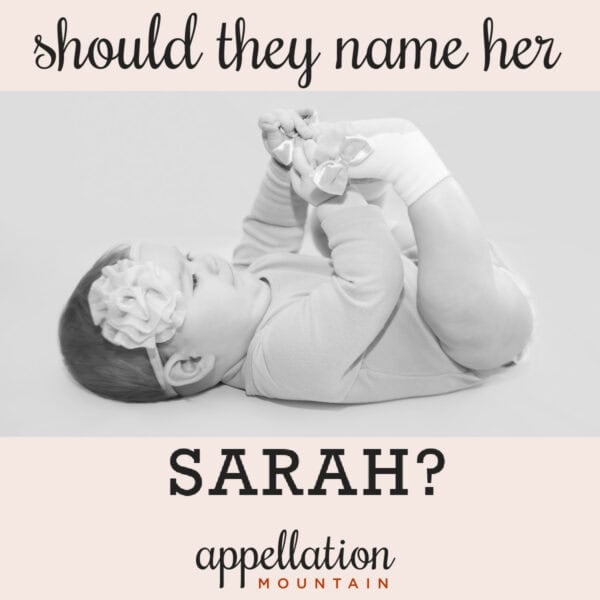 baby girl with dark hair wearing floral headband resting on back holding feet; classic not boring girl names like Sarah