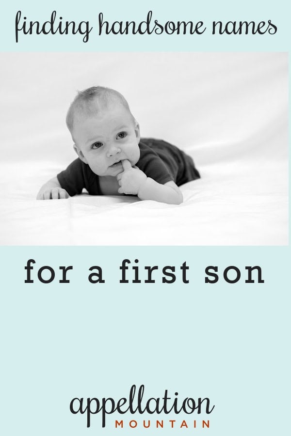 baby boy wearing dark onesie propped up on stomach with finger in his mouth; handsome boy names