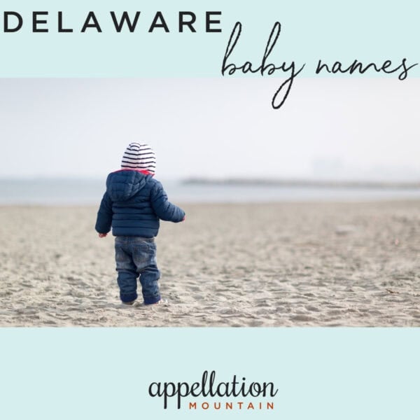 toddler standing on beach in winter wearing jeans, navy winter jacket, and striped knit hat; Delaware baby names