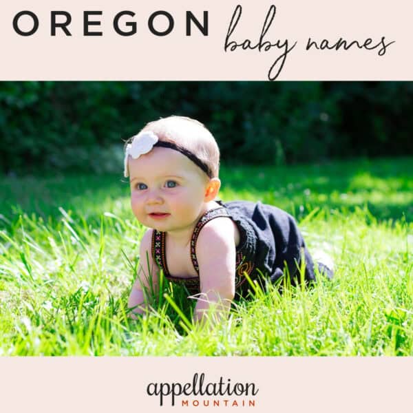 baby girl wearing brown overalls and floral headband kneeling in grass; Oregon baby names