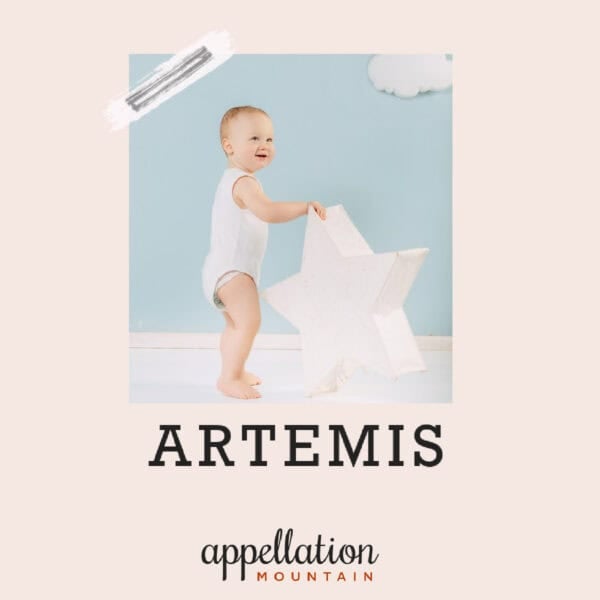 baby in white onesie standing with large white star; baby name Artemis