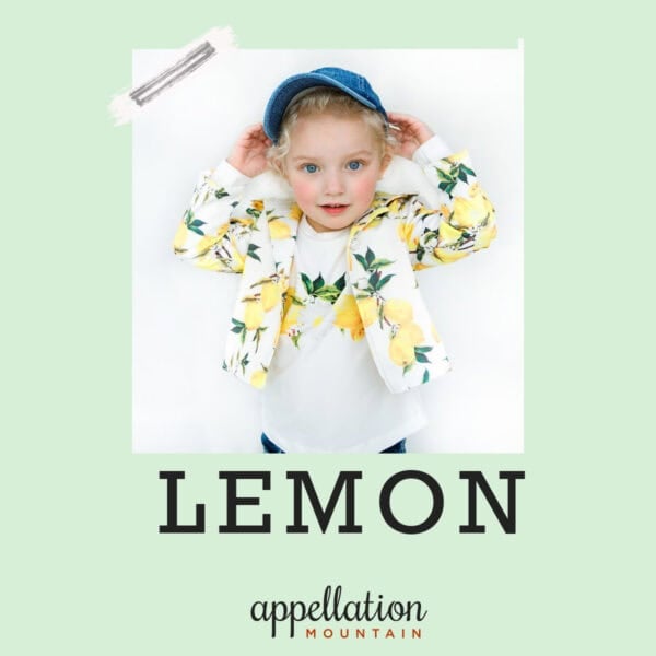 girl with blonde curls wearing lemon print tee and jacket with blue hat; baby name Lemon